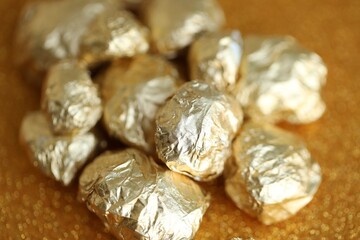 Small pile of golden nuggets on shiny gold glitter background