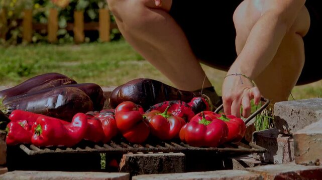 A rustic outdoor scene of vegetables grilling over a wood fire, an essential step in making traditional Romanian zacusca. The fire-roasted vegetables bring out deep, smoky flavors