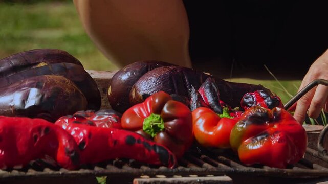 A rustic outdoor scene of vegetables grilling over a wood fire, an essential step in making traditional Romanian zacusca. The fire-roasted vegetables bring out deep, smoky flavors