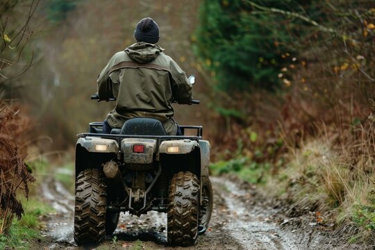 Hunter is riding a muddy four wheeler down a muddy trail in a forest