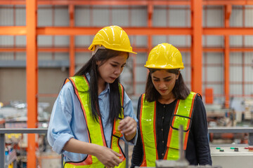 Two female mechanical engineers from different ethnicities and cultures having a discussion over a production plan. Cooperation or partnership across cultures and races in a manufacturing system