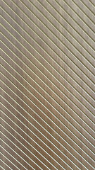 Close-up of golden brown fluted metal panels with linear shadows, ideal for modern architectural and interior design themes