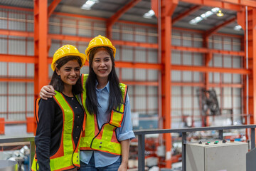 Two female mechanical engineers from different ethnicities and cultures having a discussion over a production plan. Cooperation or partnership across cultures and races in a manufacturing system