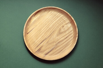 Wooden flat plates on a green background. The concept of ecological tableware. Products for modern kitchen. Zero emissions.