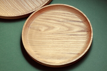 Wooden flat plates on a green background. The concept of ecological tableware. Products for modern kitchen. Zero emissions.
