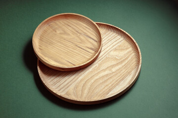 Wooden flat plates on a green background. The concept of ecological tableware. Products for modern kitchen. Zero emissions.