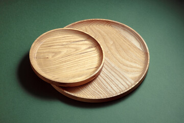 Wooden flat plates on a green background. The concept of ecological tableware. Products for modern kitchen. Zero emissions.