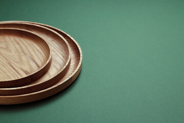Wooden flat plates on a green background. The concept of ecological tableware. Products for modern kitchen. Zero emissions.