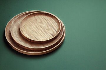 Wooden flat plates on a green background. The concept of ecological tableware. Products for modern kitchen. Zero emissions.