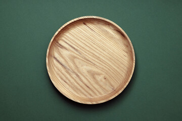 Wooden flat plates on a green background. The concept of ecological tableware. Products for modern kitchen. Zero emissions.