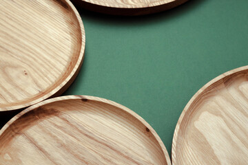 Wooden flat plates on a green background. The concept of ecological tableware. Products for modern kitchen. Zero emissions.