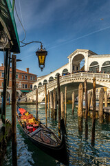 Venice, Italy - February 4, 2024: View of the beautiful Rialto Bridge spanning the Grand Canal with gondola in foreground in Venice, Italy