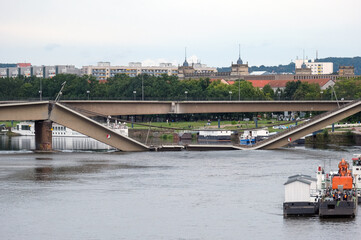 Blick auf die teileingestürzte Carolabrücke in Dresden, direkt am nächsten Morgen nach dem nächtlichen Einsturz vom Elbeufer aus, mit Maschinen, Gerät und und Bergungsschiffen – viel Copy Space