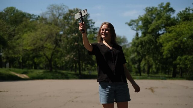portrait of a young blogger broadcasting live through a smartphone in a park on a summer day