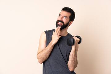 Naklejka premium Caucasian sport man with beard making weightlifting over isolated background looking up while smiling