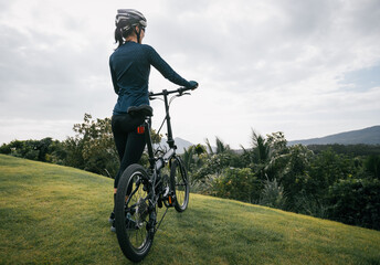 Naklejka premium Riding folding bike to tropical mountain peak