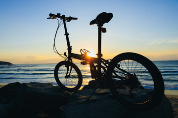 A folding bike on sunrise seaside rocka