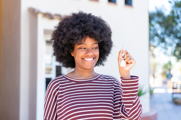 African American girl holding home keys at outdoors with happy expression