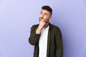 Caucasian man isolated on purple background having doubts