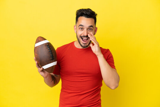 Young Caucasian man playing rugby isolated on yellow background with surprise and shocked facial expression