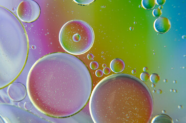 Extreme close up of oil bubbles on water surface with multicolored gradient background. Suitable...