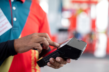 Hand of cashier hold credit card reader with blurry gas station background. Credit card payment. Buy and sell products & service. The concept of payment in gas station.