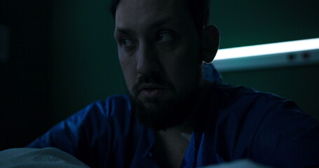 Hospitalized man, seated, visibly distressed, trembling on bed.