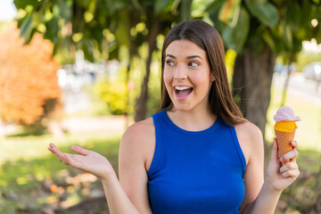 Young pretty Brazilian woman with a cornet ice cream at outdoors with surprise facial expression