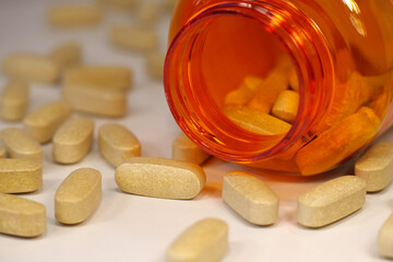 Vitamin C tablets in dosage of 1000 mg. Yellow pills and open jar on table