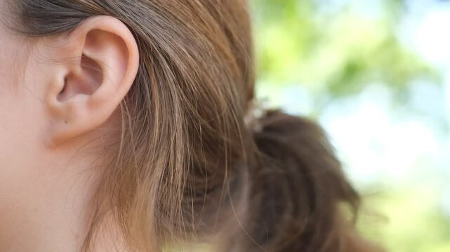 close-up of a cheerful young woman's ear talking to someone