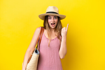 Young caucasian woman holding a beach bag isolated on yellow background intending to realizes the solution while lifting a finger up