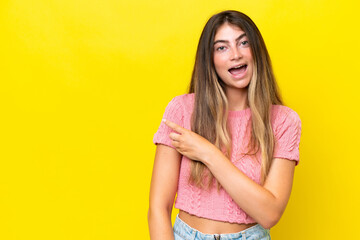 Obraz premium Young caucasian woman isolated on yellow background surprised and pointing side