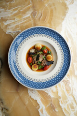 Baked beef sauce with vegetables on plate, close-up