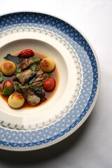 Baked beef sauce with vegetables on plate, close-up