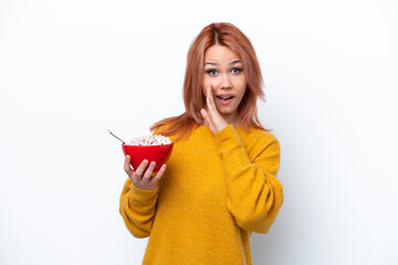 Young Russian girl holding a bowl of cereales isolated on white background whispering something