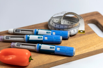  Ozempic Insulin injection pen for diabetics and weight loss and a cutting board with vegetables and a measuring tape.