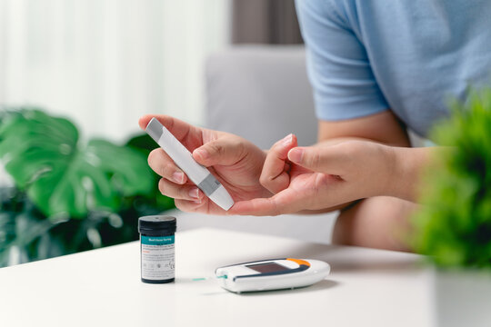 Asian woman using lancet on finger for checking blood sugar level by Glucose meter