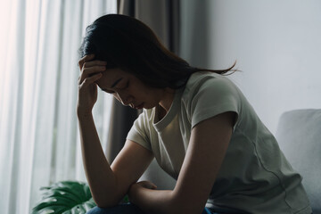 Unhappy lonely depressed woman is sitting on the couch. She looks sad and tired.