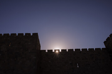 A section of the stone ramparts and walls of the Old City of Jerusalem, in silhouette with a sunstar at sunrise on Mt. Zion. © Yehoshua Halevi