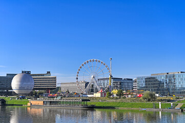 Obraz premium Hot Air Balloon and Ferris Wheel Along the Vistula River in Krakow,Poland