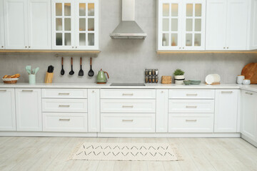 Stylish soft rug on wooden floor in kitchen