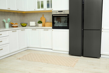Stylish soft rug on wooden floor in kitchen