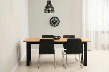 Wooden table with black chairs in stylish dining room