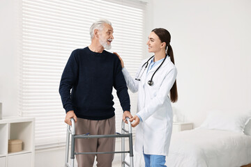 Fototapeta premium Doctor helping senior man with walking frame in clinic