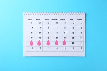 Menstruation. Calendar with marked dates on light blue background, top view