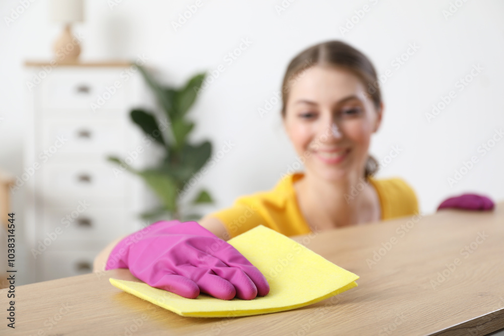 Sticker Woman cleaning table with rag at home, selective focus