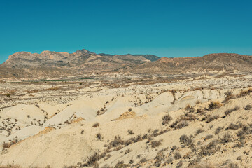 Arid mountainous landscape on a sunny day with blue sky.