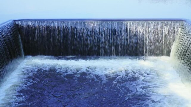Camera zoom in forward. Dike of freshwater lake with water flowing rapids. During the rainy season in rural Thailand.