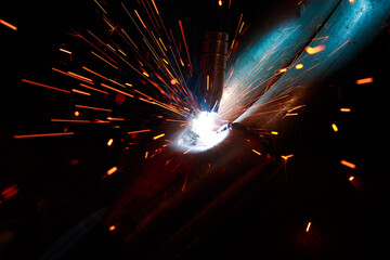 Arc welding. Welding pipes in inert gases. MIG / MAG. A bright flash of light and a sheaf of sparks.
