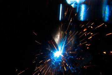 Arc welding. Welding pipes in inert gases. MIG / MAG. A bright flash of light and a sheaf of sparks.
